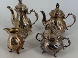 three pieces of silver tea and coffee set on a white surface