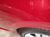 a close up of a red car with a denting on it