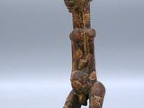 an old wooden figurine of a man sitting on a stool