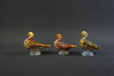 three glass birds sitting on top of each other on a black surface