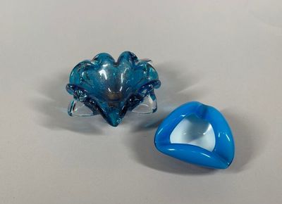 two pieces of blue glass sitting on a white surface