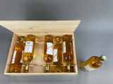 four bottles of wine in a wooden box next to a bottle of wine