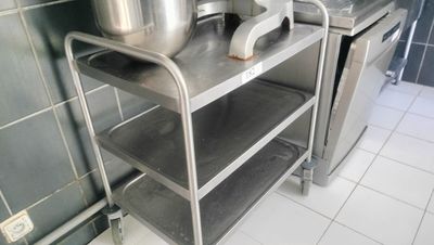 a metal shelf with pots and pans on it in a kitchen