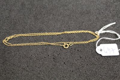 a gold chain with a tag attached to it on a black surface