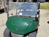 une voiturette de golf verte garée sur un parking en gravier