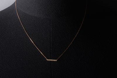 un collier en or avec un pendentif en forme de barre autour du cou d'un mannequin