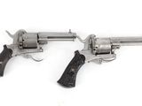 two revolvers on a white background, one with a wooden handle