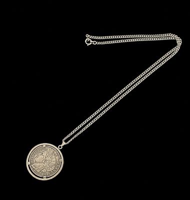 une image représentant un collier en argent avec une pièce suspendue à une chaîne