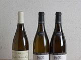 trois bouteilles de vin sont alignées sur une table en bois