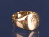 an image of a gold signet ring on a blue surface