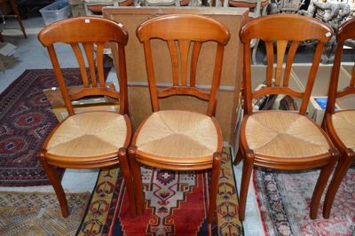 Trois chaises en bois aux assises tressées sont posées sur un tapis dans une pièce