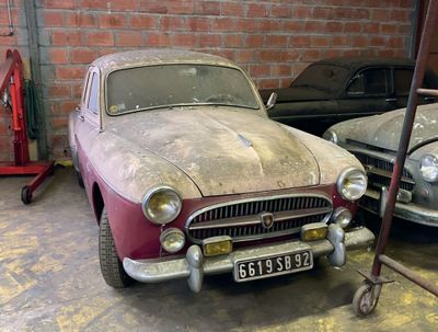 two old cars parked in a garage next to each other