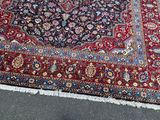 a large oriental rug on the ground with a cat sitting on it