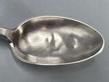 silver spoon with a face on it sitting on a table