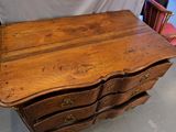 a wooden chest of drawers in a room with a chair