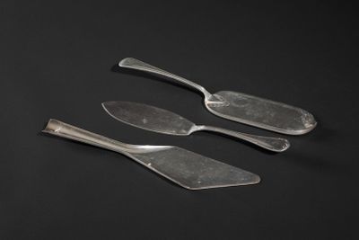 three pieces of silverware sitting on top of a black surface