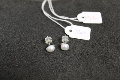 une paire de boucles d'oreilles en perles et une étiquette de prix posée sur une surface noire
