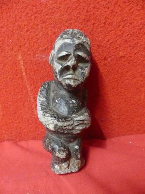 an old statue of a man sitting on a red cloth