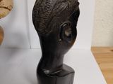 a black sculpture of a woman ' s head on a table