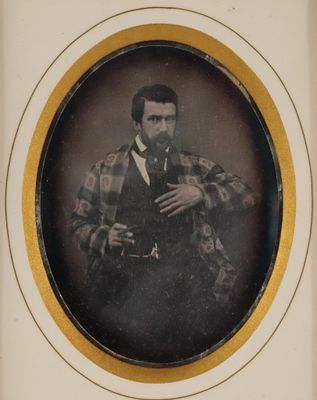 an old photo of a man in a suit and tie holding a pipe