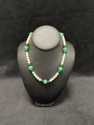 a green and white beaded necklace on a mannequin