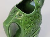 a green frog shaped vase with a hole in it ' s mouth