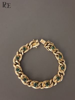 un gros plan sur un bracelet en or serti d'émeraudes