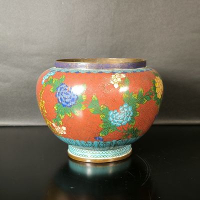 un vase rouge orné de fleurs bleues, posé sur une table