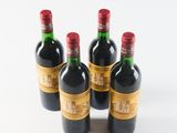 four bottles of wine are lined up in a row on a white surface