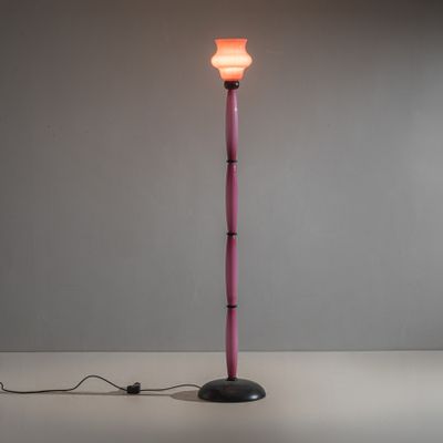 un lampadaire rose avec un pied noir et une ampoule blanche