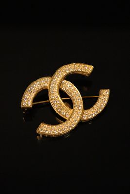 a close up of a gold brooch with diamonds on a black surface