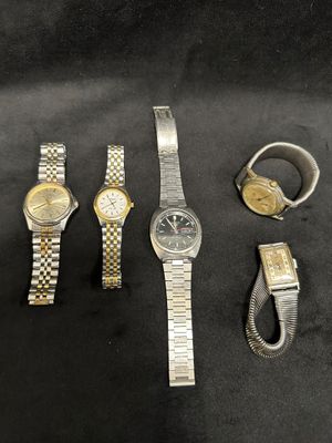 three watches and a ring are sitting on a black surface