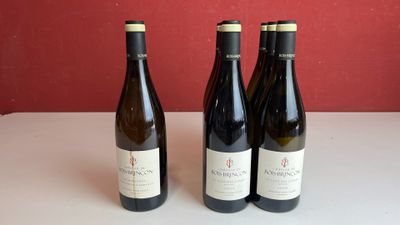 trois bouteilles de vin sont posées sur une table devant un mur rouge