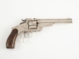 un revolver en argent avec une poignée en bois sur une surface blanche