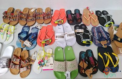 many pairs of sandals on a table next to a pair of flip flops