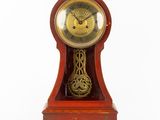 une horloge rouge avec un cadran doré sur fond blanc