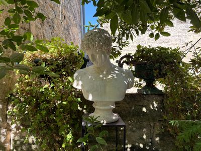 a statue of a bust in the middle of a garden