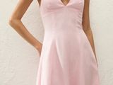 a woman in a pink dress standing against a white wall