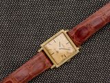 une photo d'une montre en or avec un bracelet en cuir d'alligator marron