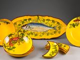 a yellow plate with a fish on it next to other plates and bowls