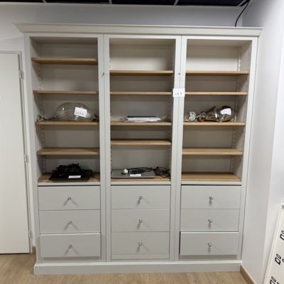 une armoire blanche avec des tiroirs et des étagères dans une pièce