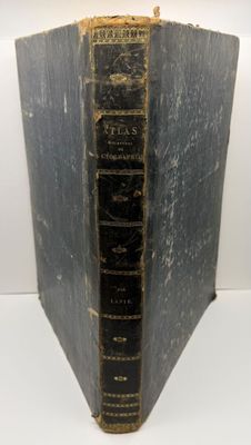 un vieux livre à la couverture noire posé sur une table blanche
