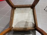 a wooden chair with a beige seat on a tile floor
