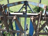 a blue gate with rusted metal parts in a grassy field