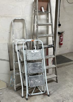 Plusieurs échelles sont empilées les unes à côté des autres dans un garage