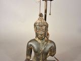 a statue of a person sitting on a table with a lamp on it