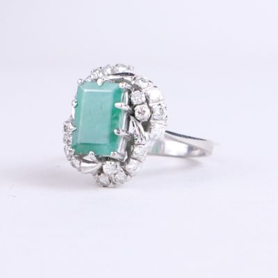 a close up of a ring with a green stone surrounded by diamonds