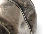 a silver bowl with a design on it on a white surface