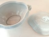 a white bowl with a lid sitting next to a blue bowl with a lid