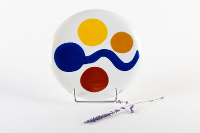 une assiette blanche ornée d'un motif bleu, jaune et rouge